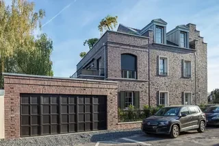 Backstein-Stadtvilla in Düsseldorf mit Garage im Vordergrund, klassischer Fassadenordnung und hellen Sprossenfenstern