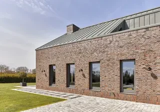 Modernes Einfamilienhaus in Hamburg mit roter Backsteinfassade und Rheinzink Stehfalz-Metalldach, geplant von Architekt Gulotta.