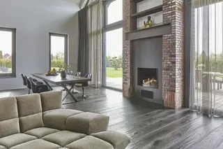 Hochwertiger Wohnbereich mit Kamin, Sichtklinker und bodentiefen Fenstern in modernem Einfamilienhaus in Hamburg.