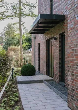 Eingang des Klinkerhauses mit schwarzem auskragendem Vordach, dunkler Haustür und Wittmunder Klinker Sortierung 68 im Dünnformat.