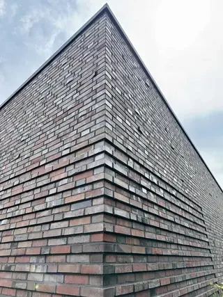 Gebäudeecke mit rotbunter Klinkerfassade und plastischer Fassadenstruktur